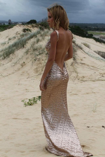 Woman in a sparkly dress standing on a sandy dune with a cloudy sky.
